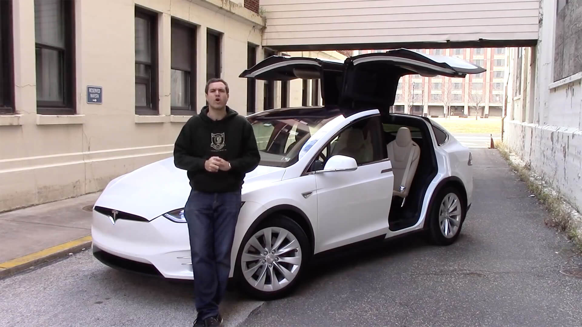 Here’s Why the Tesla Model X Is an Awful Car Doug DeMuro standing in front of a Tesla car.